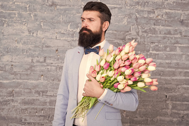 Romantic gift. Macho getting ready romantic date. Tulips for her. Man well groomed tuxedo bow tie hold flowers bouquet. From sincere heart. Things that make man gentleman. Romantic man with flowers - Foto, afbeelding