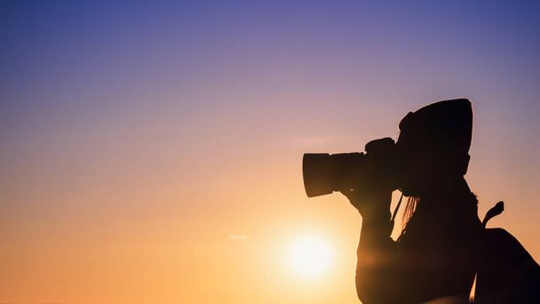 Jeune femme photographe prenant des photos avec coucher de soleil sur fond naturel de montagne
. - Photo, image