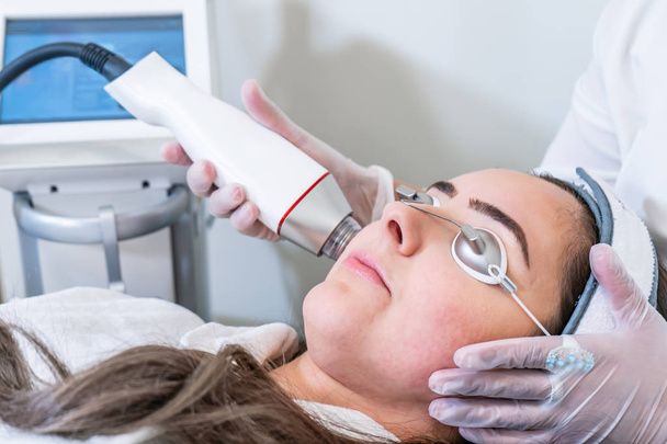 Esteticista aplicando microagulhas de rádio frequência no rosto de uma mulher para tratamentos de aperto de pele em uma clínica de beleza
. - Foto, Imagem