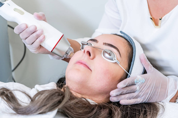 Güzellik kliniğinde cilt sıkılaştırma tedavileri için bir kadının yüzüne radyo frekansı microneedling handpiece uygulayarak Güzellik. - Fotoğraf, Görsel