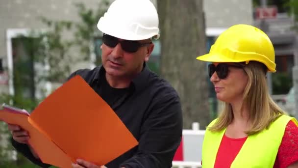 Senior Construction Site Manager met uitleg over zijn jonge blonde trainee de projecten - Video