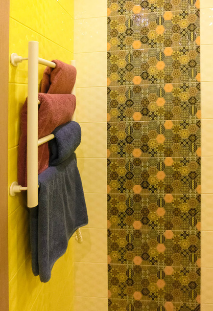 Banheiro vazio com parede de chuveiro de cor cinza atrás de rack de aquecimento de metal branco
 - Foto, Imagem