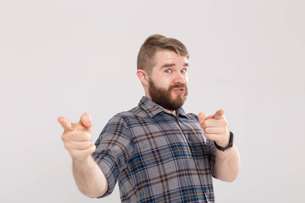 Joven hombre excitado con barba, con el dedo apuntando hacia la cámara sobre un fondo blanco
 - Foto, Imagen