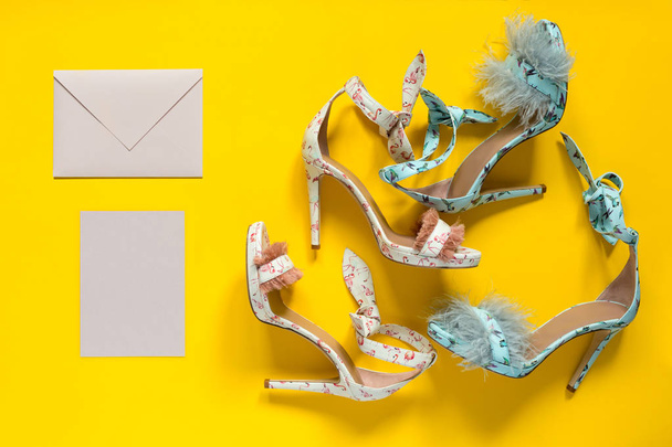 Summer women's high-heeled shoes. Flamingo hummingbirds and feathers. A pink envelope and a card. Yellow paper background. - Фото, зображення