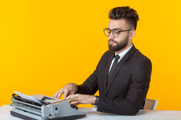 Oldalnézetből egy fiatal, bájos férfi üzletember hivatalos öltözékben és szemüveg gépelés egy írógép szöveget. Az üzleti ügyek és ötletek fogalma. - Fotó, kép