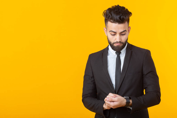 Charming young self-confident businessman wearing formal clothes posing on a yellow background with copy space. Concept of business and success. - Фото, изображение