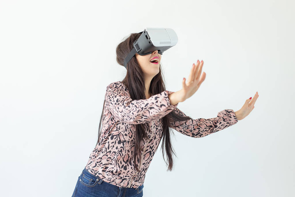 Young woman watches a movie with glasses of virtual reality standing on a white background. The concept of new features and modern technology - Фото, зображення