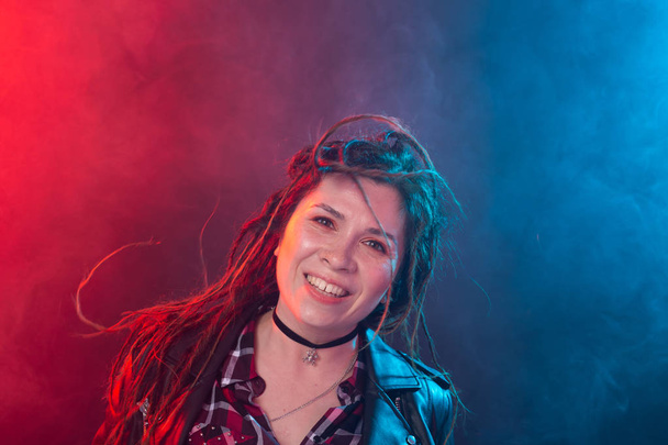 Portrait of young woman with dreadlocks having fun over the dark background - Photo, Image