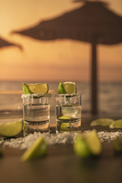 Un par de lujosos chupitos de tequila con rodajas de limón encima y sobre la mesa
 - Foto, imagen