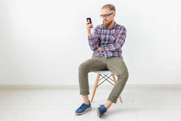 Jeune homme barbu hipster assis sur le fond blanc avec espace de copie
 - Photo, image