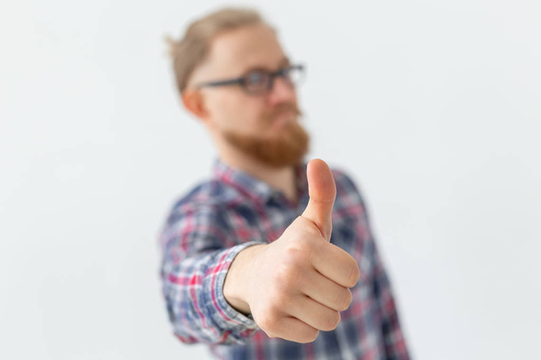 people, style and fashion concept - young bearded man in glasses with thumb up on white background. - Zdjęcie, obraz