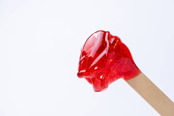 Pasta de açúcar vermelho líquido ou cera para depilação em um close-up de pau
 - Foto, Imagem