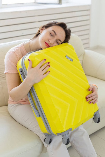 Trip, travel and holidays concept - young woman hugging her yellow suitcase - Fotografie, Obrázek