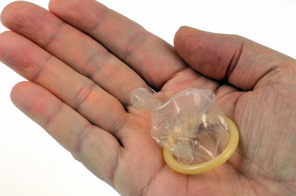 Αρσενικό προφυλακτικό στην παλάμη ενός χεριού κοντά σε λευκό φόντο - Φωτογραφία, εικόνα