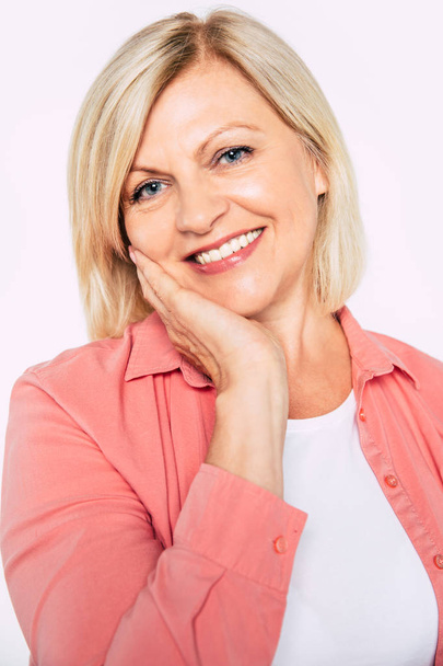 Close-up portret van gelukkig glimlachen en mooie blonde Senior vrouw geïsoleerd in Studio en poseren met glimlach op camera - Foto, afbeelding