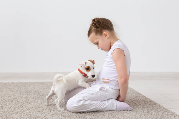 Kedvtelésből tartott állatok és állati fogalma - gyermek lány Jack Russell Terrier kiskutya játszik - Fotó, kép