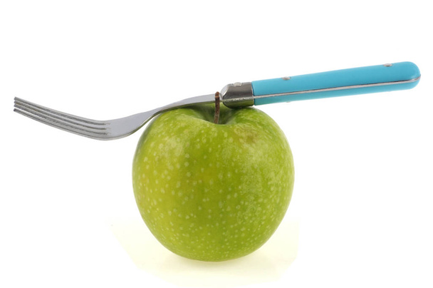 tenedor equilibrado sobre una manzana abuela herrero de cerca sobre fondo blanco
 - Foto, imagen