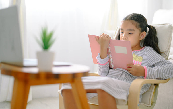 onnellinen lapsi pieni aasialainen tyttö lukee kirjoja pöydällä t
 - Valokuva, kuva