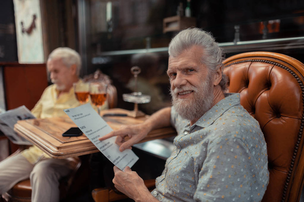 Bearded man choosing dish having lunch with friend - Фото, изображение