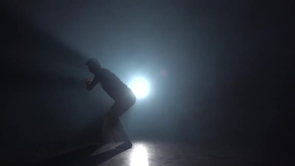 Silhouette mâle dans l'obscurité contre les projecteurs de lumière pratiquant la capoeira. Mouvement lent
. - Séquence, vidéo