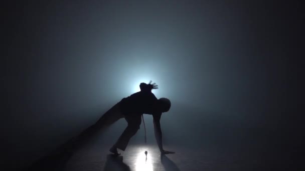 Capoeira. Silhouette of male in darkness against light spotlight. Slow motion. - Footage, Video