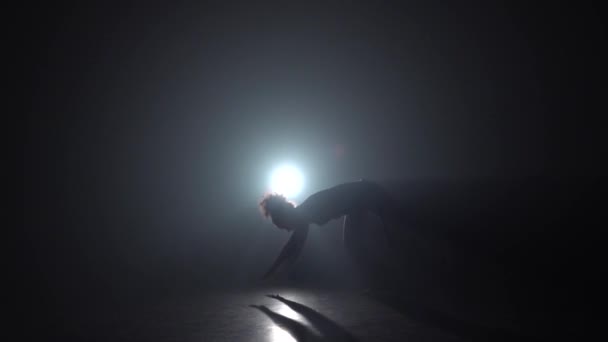 Capoeira. Silhouette of woman in darkness against light spotlight. Slow motion. - Footage, Video