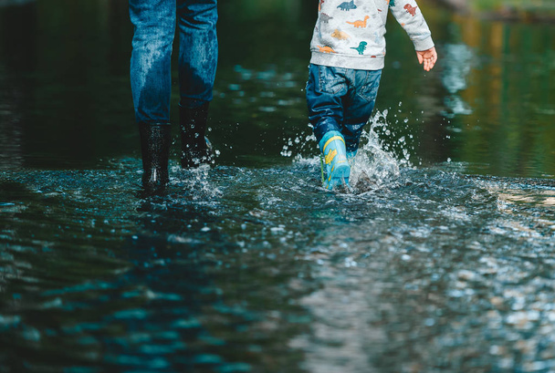 夏の水たまりで母親と息子のクローズアップ脚。背面図 - 写真・画像