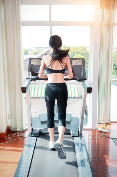 joven mujer deportiva sana corriendo o caminando en la máquina de ejercicio en el gimnasio (concepto de entrenamiento
) - Foto, imagen