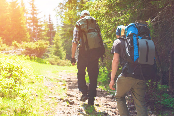 Двоє друзів подорожують в горах з рюкзаками
 - Фото, зображення