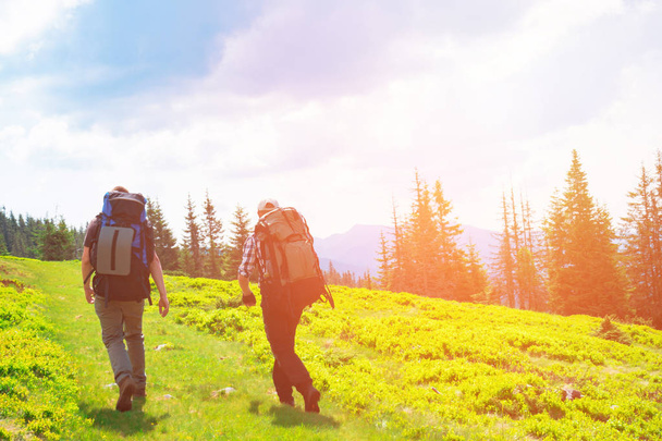 Two friends travel in mountains with backpacks - Fotó, kép