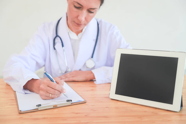 médico escribiendo nota con el comprimido e informar al paciente (concepto médico
) - Foto, imagen