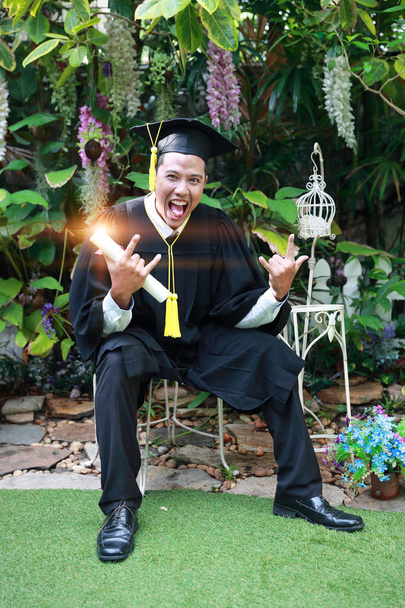 Feliz hombre graduado sosteniendo y mostrando grado, idea para el concepto de educación
 - Foto, Imagen