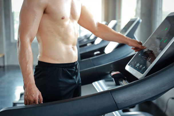 image of healthy and sexy caucasian muscle man in shirtless who setting up running machine in gym  - Fotoğraf, Görsel