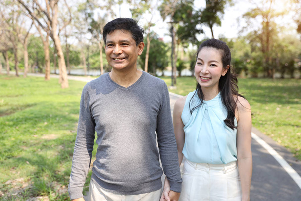 asian couple walking and talking in the park with happy face  - Фото, изображение