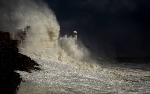 Шторм над маяком Порткаул и пирсом в челюсти шторма на побережье Южного Уэльса, Великобритания
. - Фото, изображение