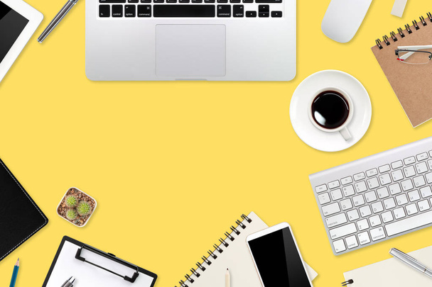 platte werktafel met laptopcomputer, kantoorbenodigdheden, koffiebeker, tablet en mobiele telefoon op gele pastelachtergrond - Foto, afbeelding