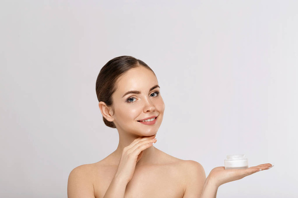 Beauty Face of Woman Concept. Skin care. Portrait of female model  holding and applying cosmetic moisturizing cream and touch own face. Skin Protection. Cosmetology. Spa - Foto, afbeelding