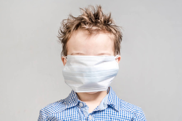 Boy with a closed medical mask face on a gray background in the  - Фото, изображение