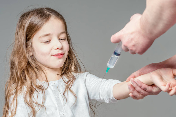 The girl is vaccinated against a gray background. Isolated. - Foto, imagen