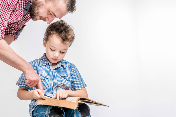 Man and boy reading a book on a white background in the studio. - Foto, Imagen
