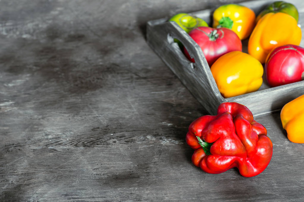 Imperfect natural peppers and tomatoes on an old wooden tray on a dark background. Copy Space. - Foto, Bild