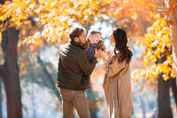 Nuori perhe hauskaa syksyllä puistossa poikansa kanssa
. - Valokuva, kuva