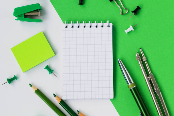 carnet et crayons avec autres fournitures scolaires isolés sur fond blanc et vert. retour à l'école
 - Photo, image