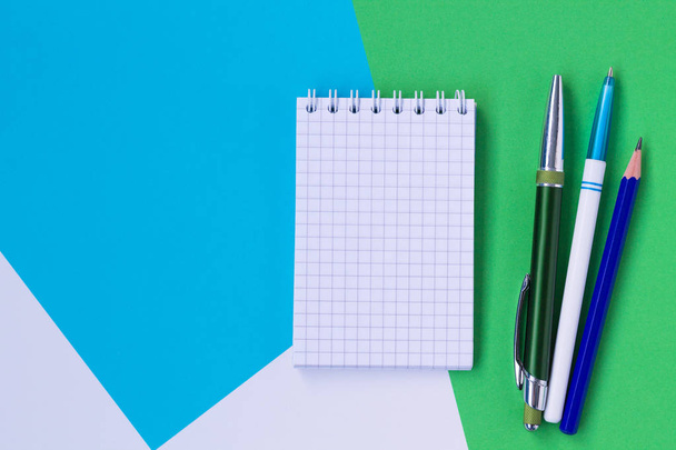 beyaz, mavi ve yeşil arka plan üst görünümünde izole defter ve kalem - Fotoğraf, Görsel