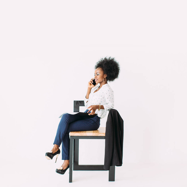 Young african american business woman talking on the phone while sitting on the chair - Фото, зображення