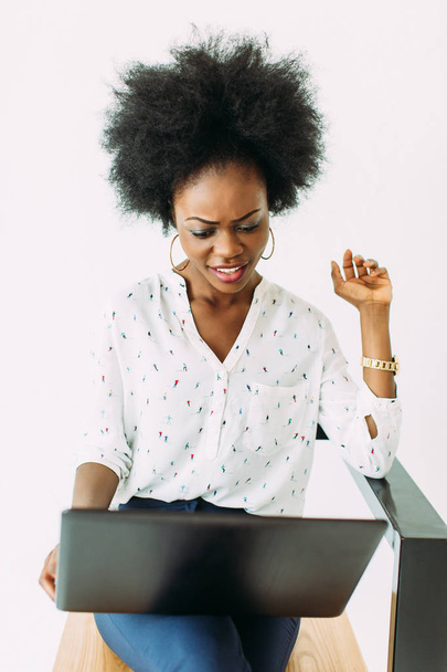 cheerful young afro american business woman concentrated and confused, using laptop, isolated on white - Fotó, kép