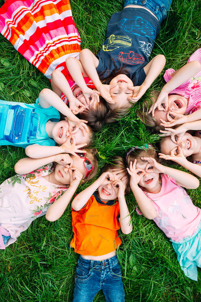 Grupa dzieci leżących na zielonej trawie w parku. Interakcje dzieci. - Zdjęcie, obraz