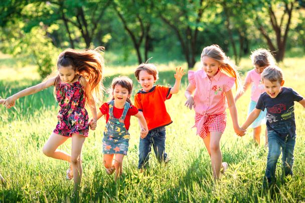 Large group of kids, friends boys and girls running in the park on sunny summer day in casual clothes . - Photo, Image