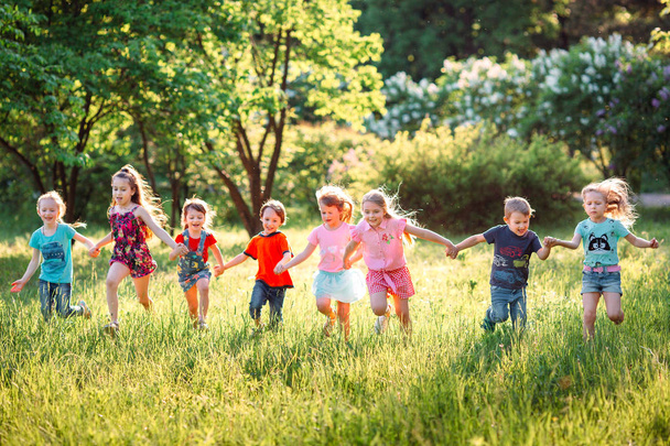 Gran grupo de niños, amigos, niños y niñas corriendo en el parque en el soleado día de verano con ropa casual . - Foto, imagen