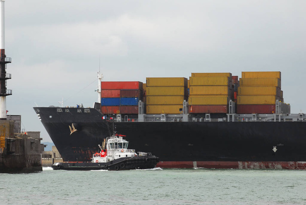 Tugboat naast een containerschip - Foto, afbeelding